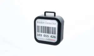 En svart radonmätare med streckkod och texten "Radon Detector". Kanske en present från grannar för att mäta inomhusluften.