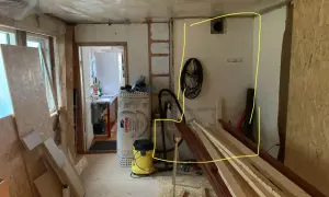 Renovering pågår. Gips mot murstock, isolering, byggmaterial och verktyg syns.
