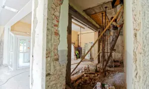 Renovering av ett sekelskiftes hus. Byggnadsställningar, rivningsmaterial och arbetare syns i det pågående arbetet.