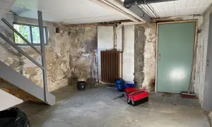 Källare med trappa, fönster, dörr, element och rör. Verktyg och hinkar står på golvet. Förberedelser för FTX ventilation och radonmätning.