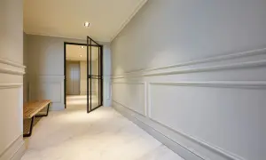 Elegant hall med stuckatur och marmorgolv. En öppen glasdörr leder in till ett ljust rum.
