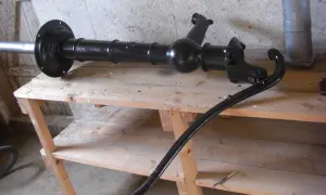 Svartmålad gårdspump, redo för renovering. Den ligger på en träbänk i ett garage.