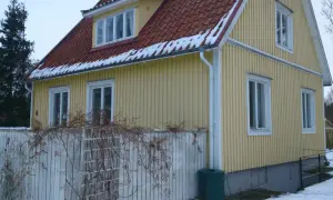Gult 40-talshus med tegeltak och snö på takfoten. Ett staket med klätterväxter löper framför huset. Planer på att renovera 40-talshus?