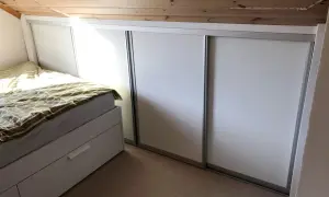 Säng och garderob i ett rum med snedtak. Perfekt för att renovera kattvind och maximera förvaringen.