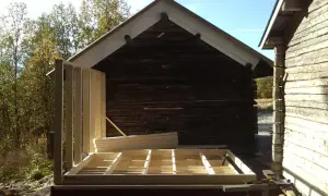 Bygga ut timmerhus. Ny stomme reses vid ett gammalt timrat hus.