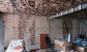 Bygga om hus: synliga bjälkar, isolering och tegelväggar vittnar om renovering. Material och verktyg ligger utspridda.