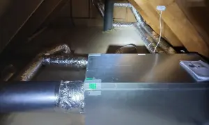 Ventilationssystem i en vind med isolerade rör och en aggregatbox. Systemet är installerat för att hantera kallras och säkerställa god luftkvalitet.