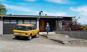 Man i kostym går mot ett funkishus från 60-talet med en gul Range Rover parkerad utanför.