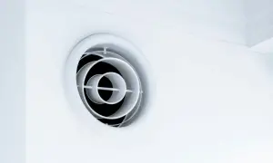 En vit, rund ventilationsgaller i taket. Den har koncentriska cirklar som skapar ett modernt utseende.