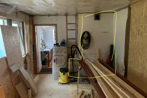 Renovering pågår. Gips mot murstock, isolering, byggmaterial och verktyg syns.