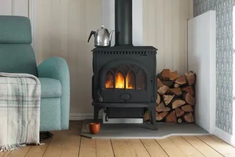 En mysig vrå med en sprakande kamin, vedhög och en bekväm fåtölj. En **mura skorsten** leder röken ut.