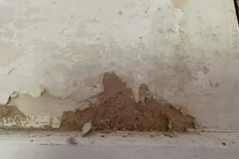 Skadad vägg med flagnande färg och synliga fibrer, misstänkt tretex asbest.