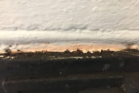 Detaljbild av en murstock som behöver målas. Fläckar och ojämnheter syns tydligt.