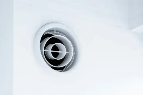 En vit, rund ventilationsgaller i taket. Den har koncentriska cirklar som skapar ett modernt utseende.