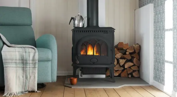 En mysig vrå med en sprakande kamin, vedhög och en bekväm fåtölj. En **mura skorsten** leder röken ut.