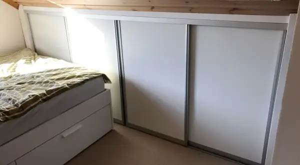 Säng och garderob i ett rum med snedtak. Perfekt för att renovera kattvind och maximera förvaringen.