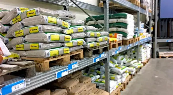 Stora lagerhyllor fyllda med säckar av byggmaterial, som bruk och cement, från kc bruk.