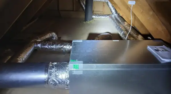 Ventilationssystem i en vind med isolerade rör och en aggregatbox. Systemet är installerat för att hantera kallras och säkerställa god luftkvalitet.