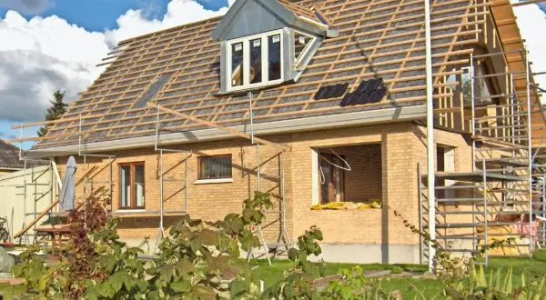 Bygga ut gammalt hus med nytt tak och takkupa. Ställningar runt huset visar på pågående renovering.