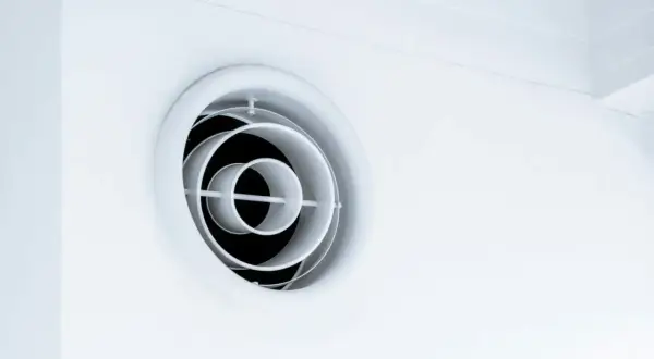 En vit, rund ventilationsgaller i taket. Den har koncentriska cirklar som skapar ett modernt utseende.