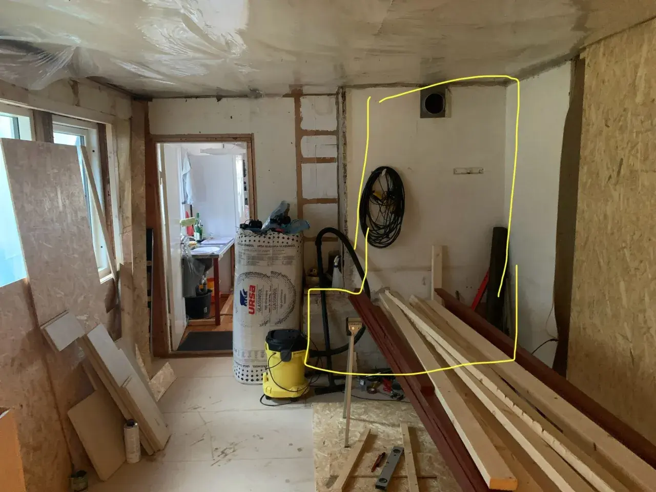 Renovering pågår. Gips mot murstock, isolering, byggmaterial och verktyg syns.