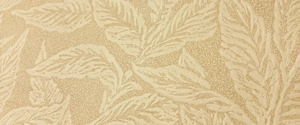 En beige tapet med ett mönster av stiliserade blad, typiskt för en tapet 1940-tal. Mönstret har en texturerad yta.