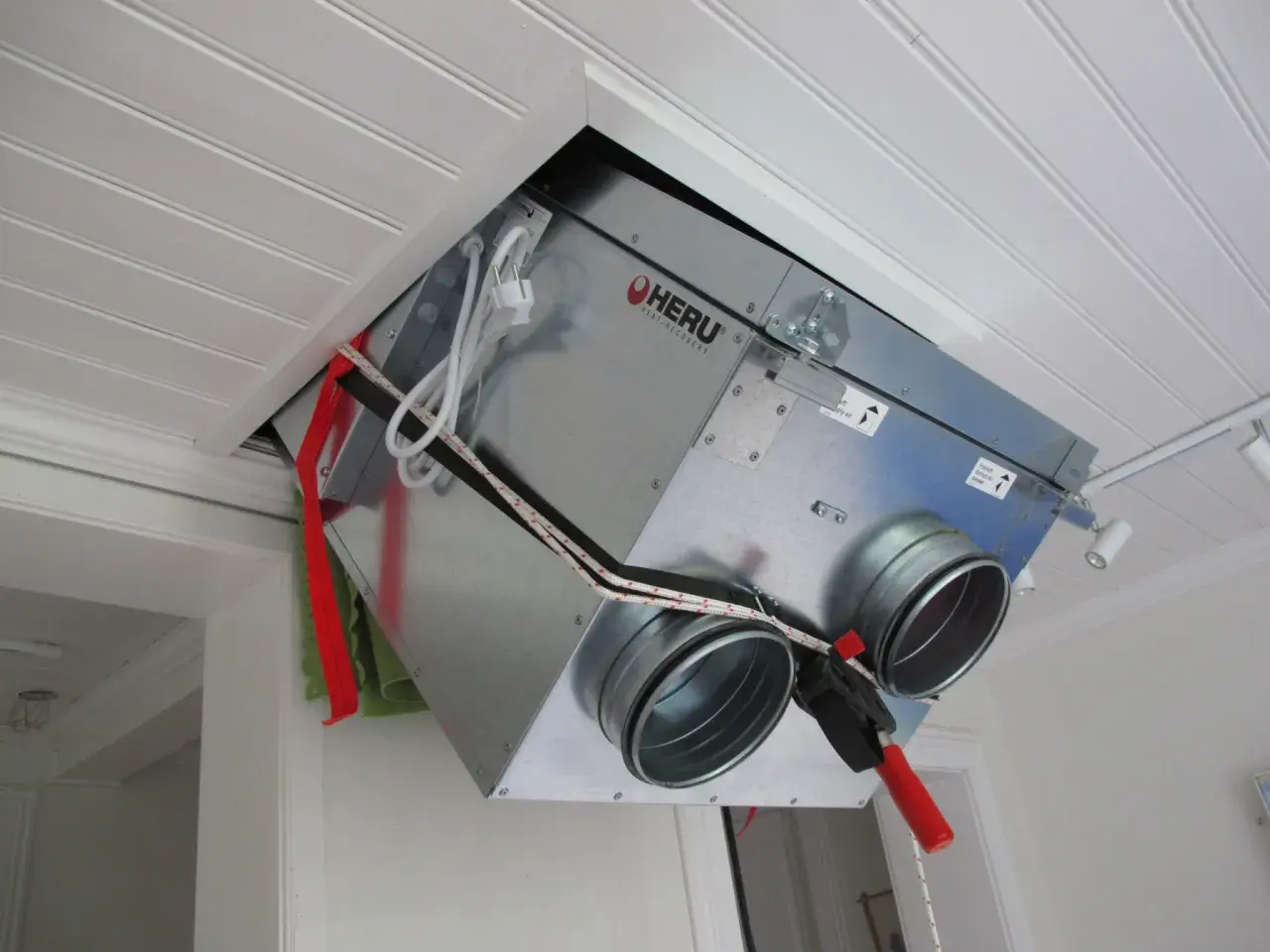 Ett FTX-aggregat vindmonterat i taket. Enheten är av märket HERU och har anslutningar för ventilation.