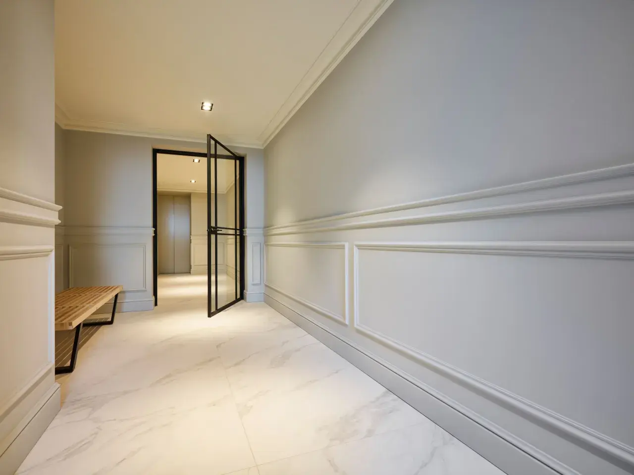 Elegant hall med stuckatur och marmorgolv. En öppen glasdörr leder in till ett ljust rum.