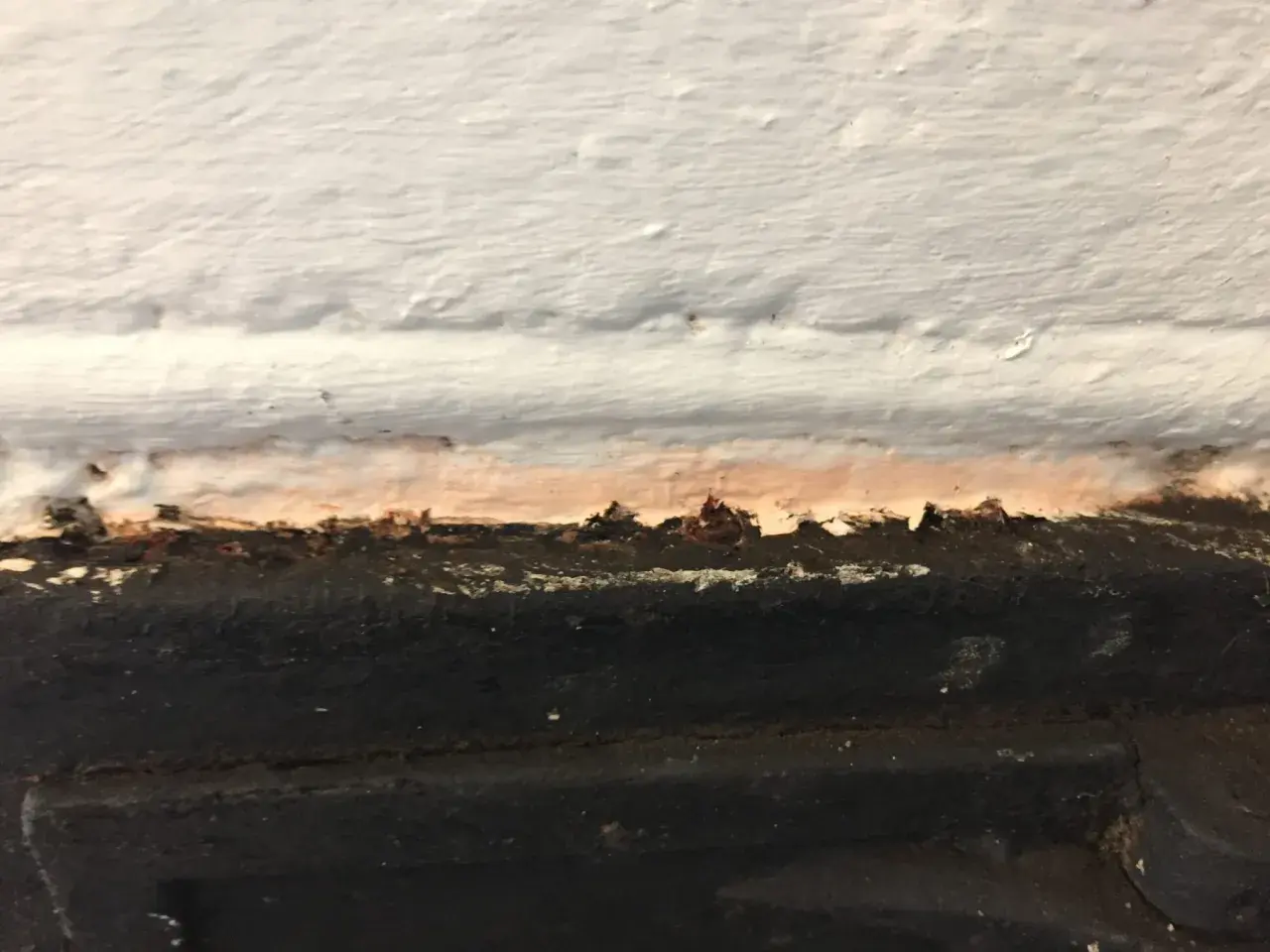 Detaljbild av en murstock som behöver målas. Fläckar och ojämnheter syns tydligt.