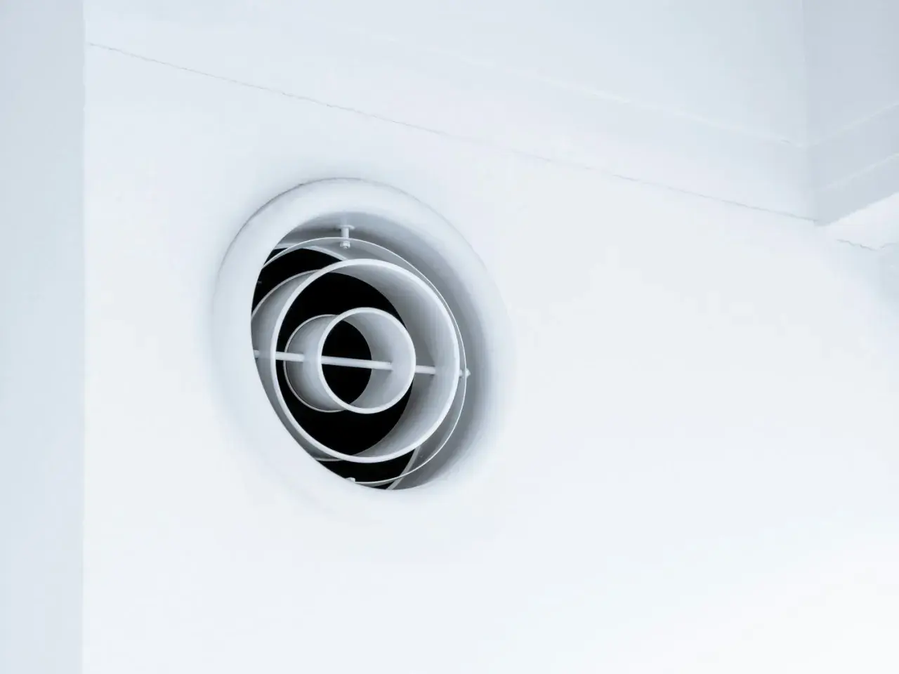 En vit, rund ventilationsgaller i taket. Den har koncentriska cirklar som skapar ett modernt utseende.