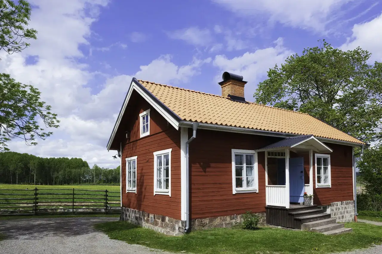 R&ouml;tt tr&auml;hus med tegeltak och skorsten. Planer p&aring; att bygga ut gammalt hus i lantlig milj&ouml; med &auml;ng och skog i bakgrunden.