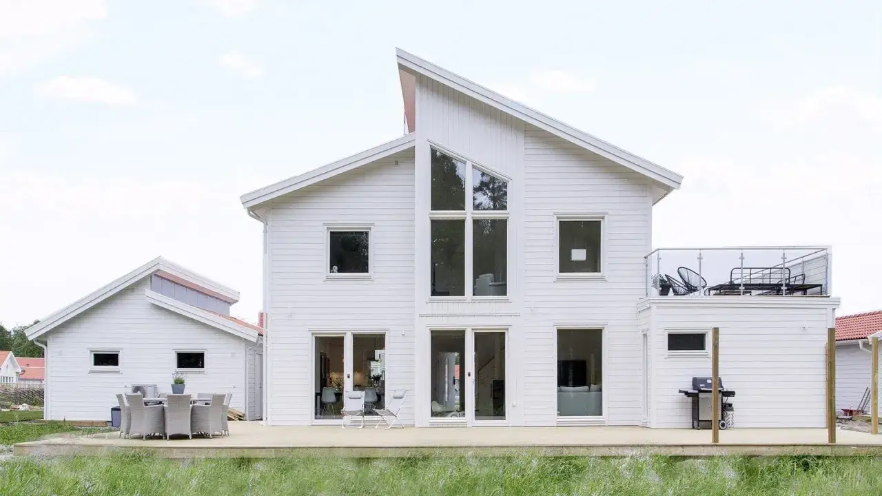 Vitt modernt hus med stora f&ouml;nster och altan. En bra byggare har skapat detta dr&ouml;mhem.