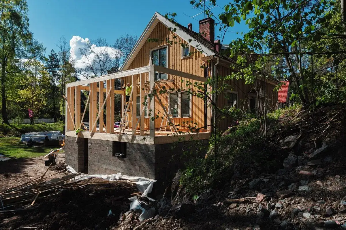 Husbyggnation i skogen. En ny stomme byggs p&aring; ett befintligt hus. Fr&aring;gan 