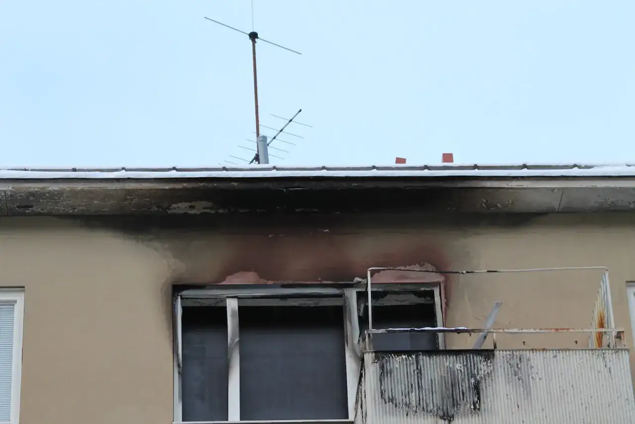 Skadad takfot konstruktion med sot och r&ouml;df&auml;rgade m&auml;rken efter en brand. Sn&ouml; ligger p&aring; takkanten.