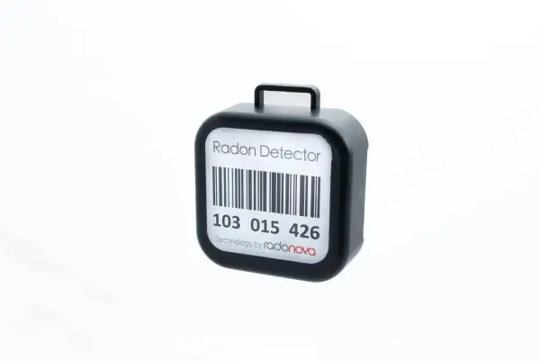 En svart radonmätare med streckkod och texten "Radon Detector". Kanske en present från grannar för att mäta inomhusluften.