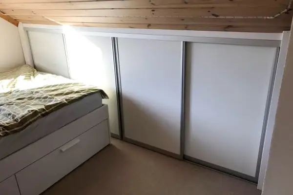 Säng och garderob i ett rum med snedtak. Perfekt för att renovera kattvind och maximera förvaringen.