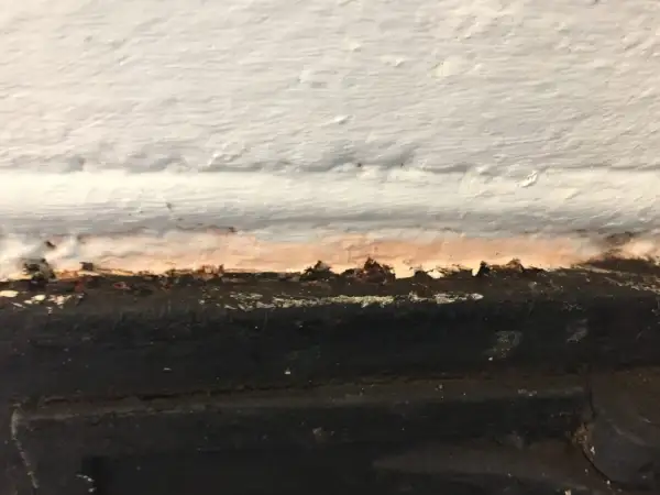 Detaljbild av en murstock som behöver målas. Fläckar och ojämnheter syns tydligt.