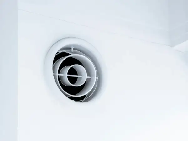 En vit, rund ventilationsgaller i taket. Den har koncentriska cirklar som skapar ett modernt utseende.