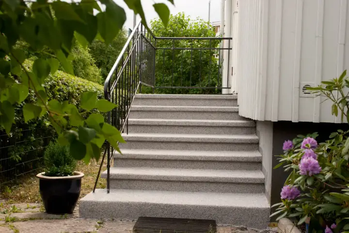 Nytt ytskikt på betongtrappa ger ett fräscht och hållbart resultat. Vackra lila rhododendronblommor ramar in entrén.